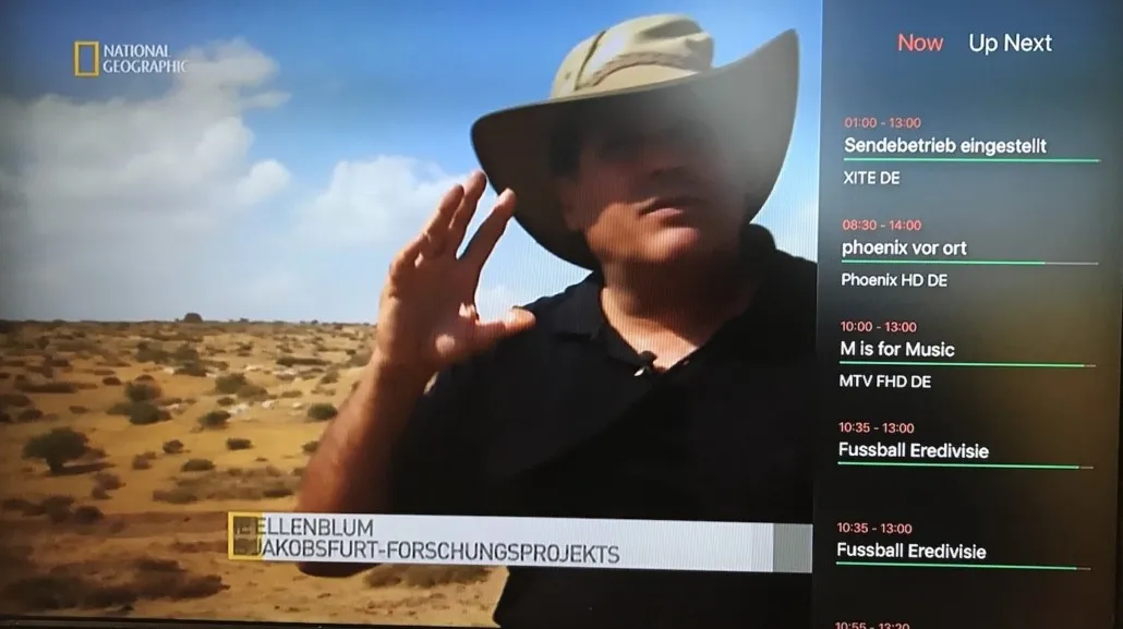 iPlayTV live channel view on Apple TV with the Now and Up Next program guide overlay
